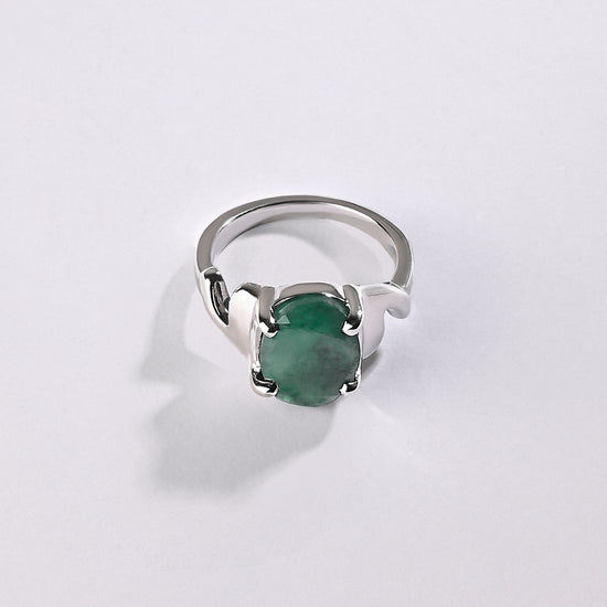 Silver ring with a green gemstone on a light gray background