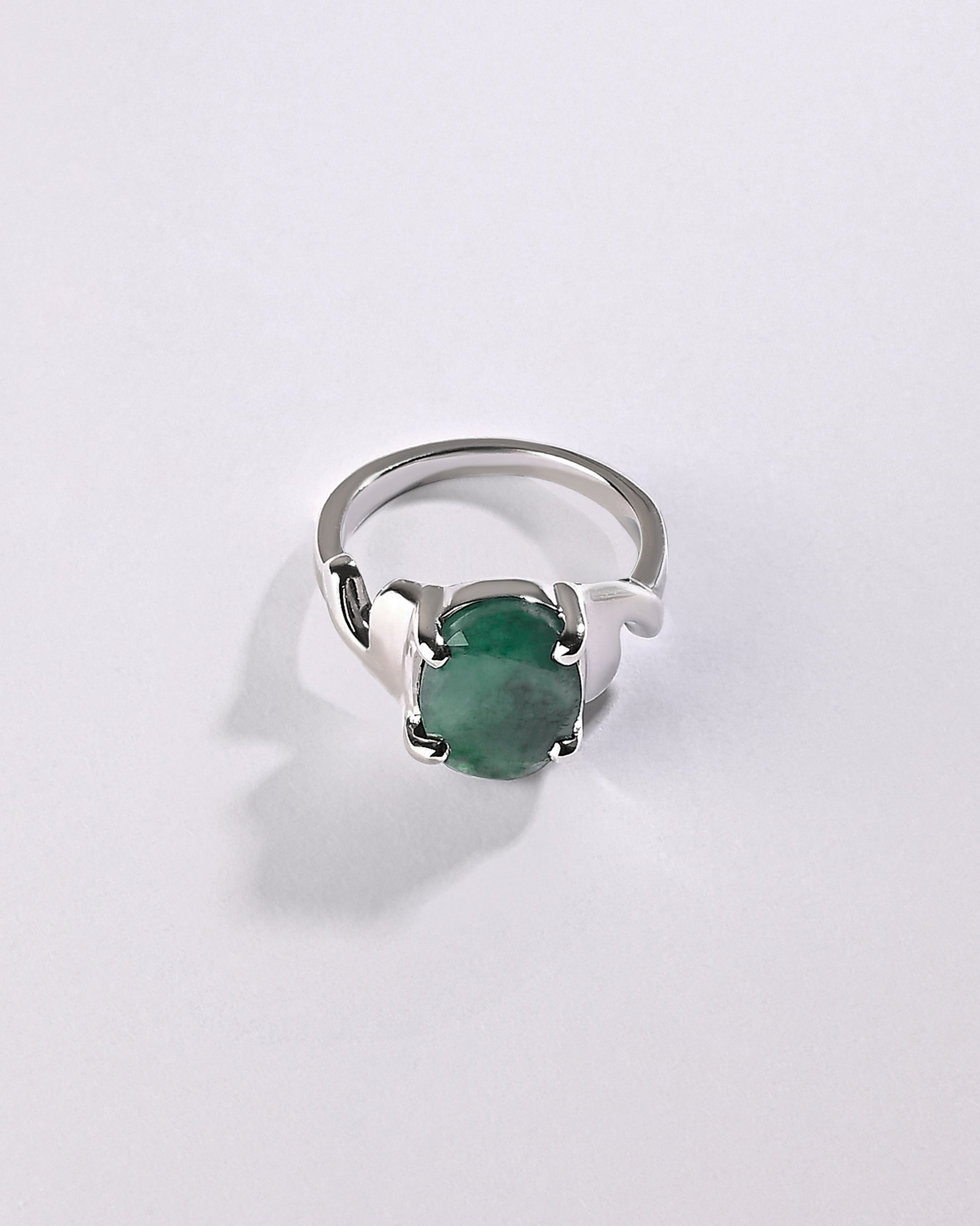 Silver ring with a green gemstone on a light gray background