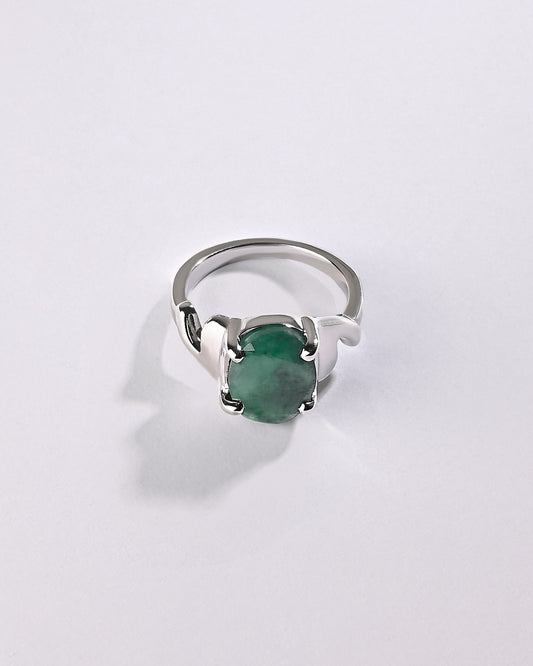 Silver ring with a green gemstone on a light gray background